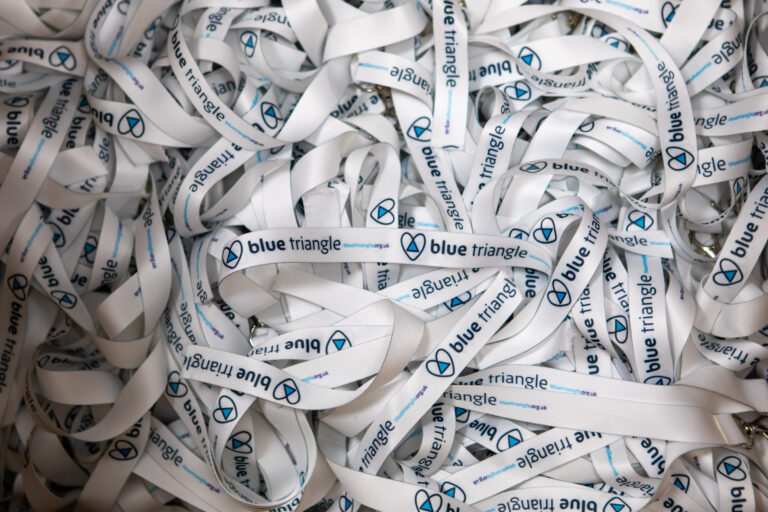 A large bundle of white lanyards with the Blue Triangle logo