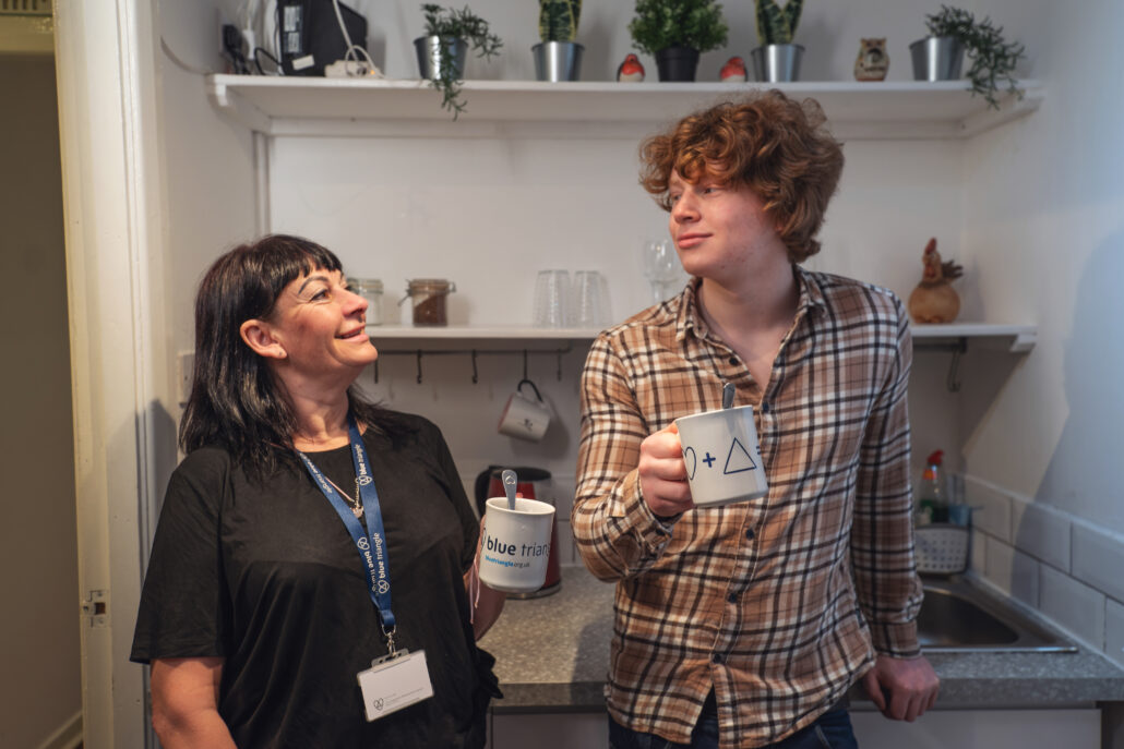 Blue Triangle staff worker and young person have a cup of tea together in a kitchen.