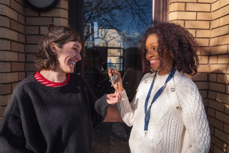 Blue Triangle worker hands a set of keys to a supported person outside a flat door