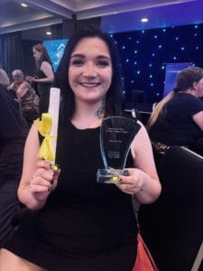 Supported person holding award.
