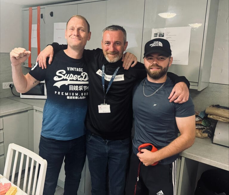 Three people looking happy, with arms around each other