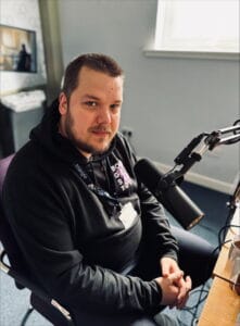 Chairman Jonathon sitting at a desk with headphones and podcast mic.